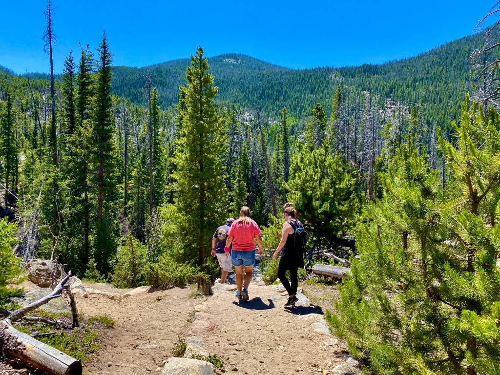 Family hiking downhill into mountains on trail