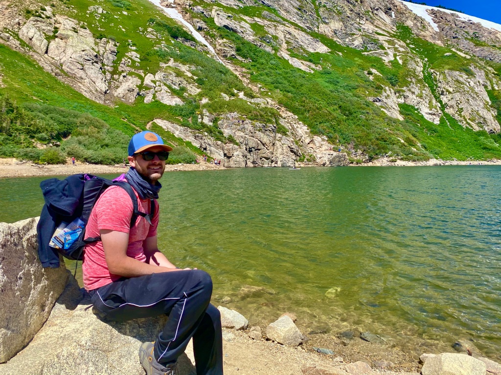 Man sitting on rock alongside the mountain lake